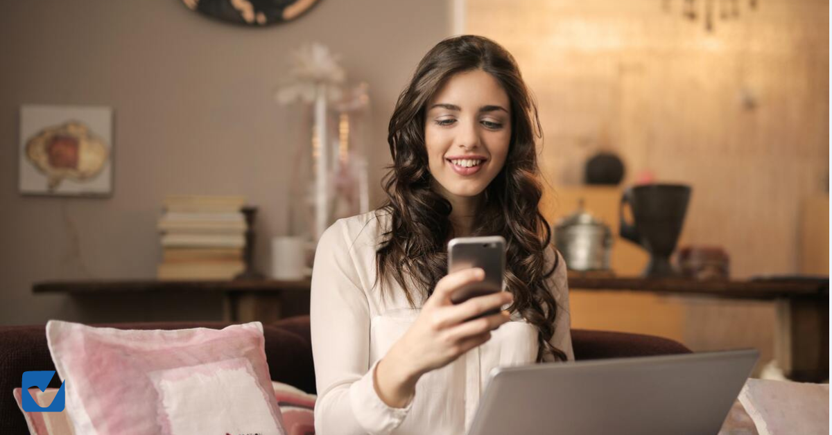 femme lorgnant son téléphone avec le sourire