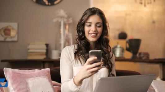 femme lorgnant son téléphone avec le sourire